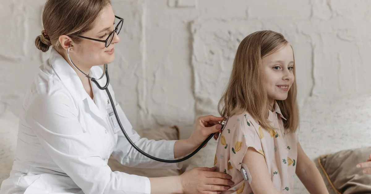 Un médecin utilise un stéthoscope lors d'un examen avec une jeune fille dans un cadre médical.