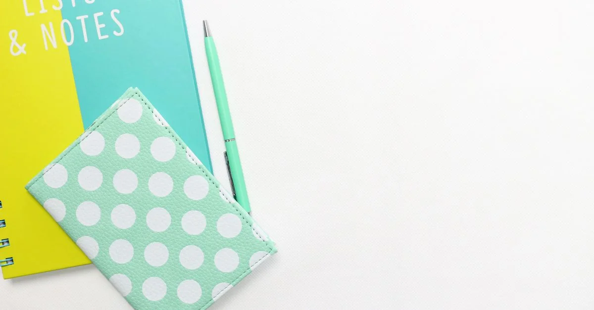 Vue de dessus d'un portefeuille à pois, d'un stylo et d'un carnet avec espace pour le texte sur fond blanc.
