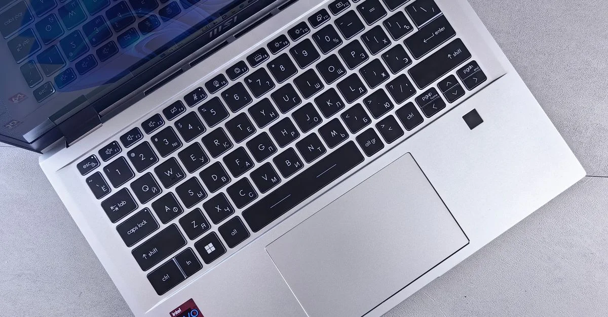 Vue de dessus d'un ordinateur portable argenté élégant avec un clavier rétroéclairé sur une surface de bureau minimaliste.