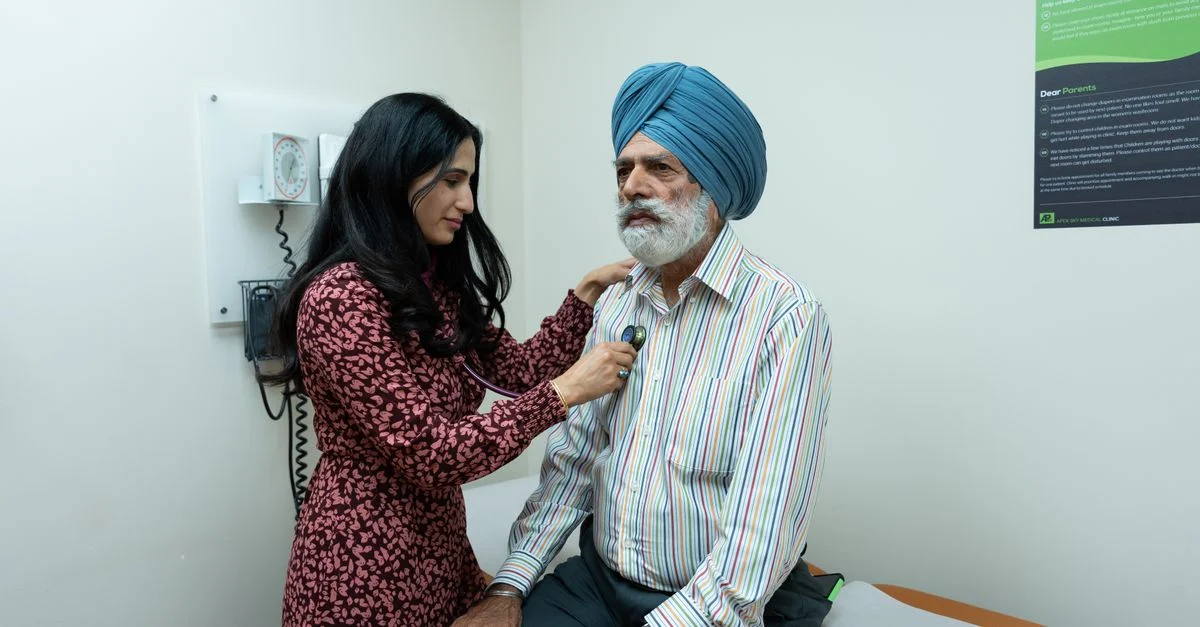 Une médecin utilise un stéthoscope pour examiner un homme senior dans une salle d'examen.
