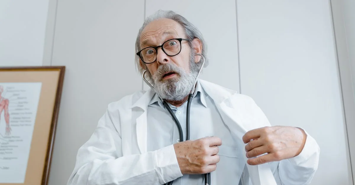 Médecin âgé surpris portant une blouse de laboratoire et un stéthoscope à l'intérieur.